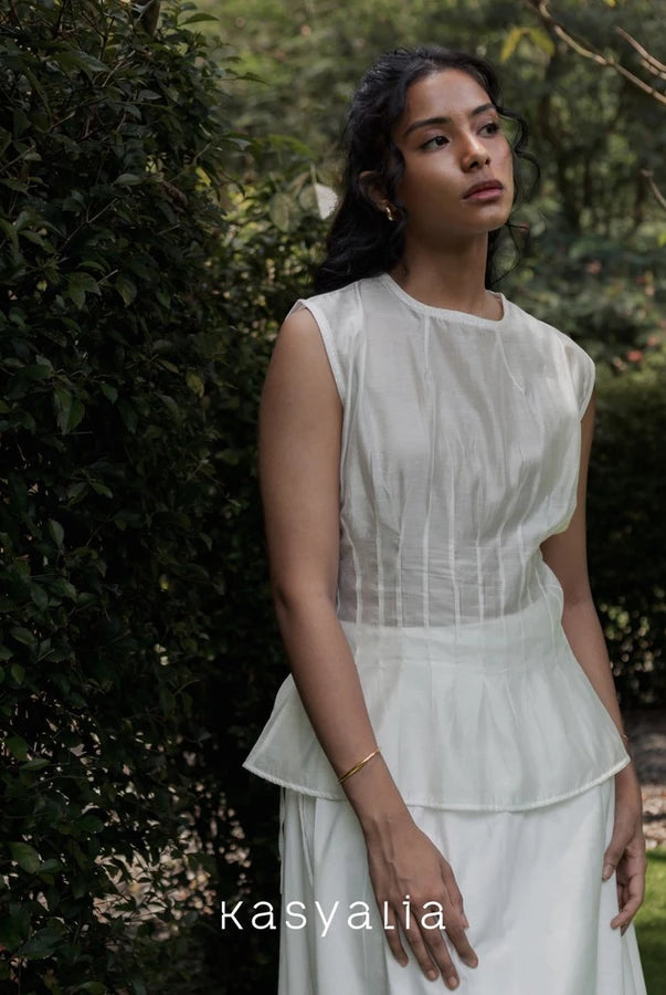 Woman wearing a cream blouse standing in a garden with 'kasyalia' branding.
