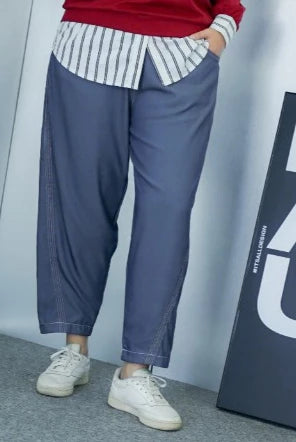 Person wearing blue wide-leg denim pants by Abame, a red sweater, and white sneakers in front of a gray wall.
Seorang pria yang mengenakan celana denim lebar berwarna biru dari Abame, sweter merah, dan sepatu kets putih di depan dinding abu-abu.