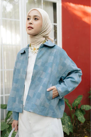 Woman wearing a light blue checkered denim jacket from Haidee Orlin with a white background