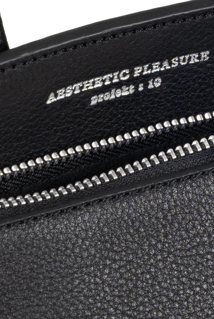Black grain leather bag with silver zipper and 'Aesthetic Pleasure' text on a white background