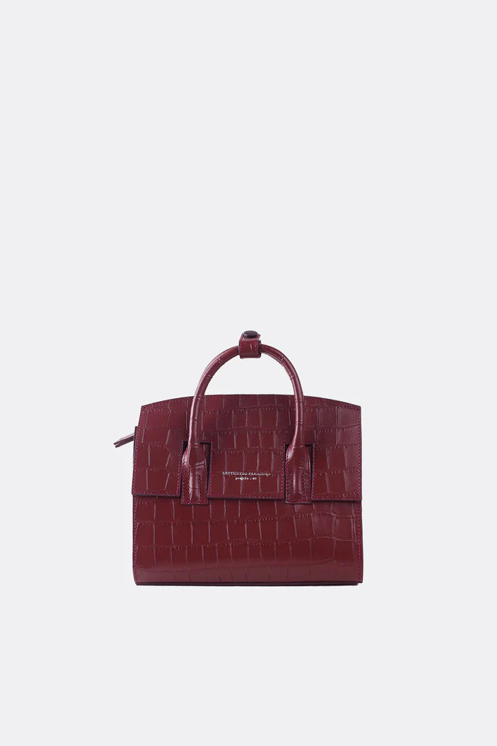 A mini-sized maroon leather handbag with a textured alligator pattern, featuring a detachable strap and silver-tone hardware by Aesthetic Pleasure.