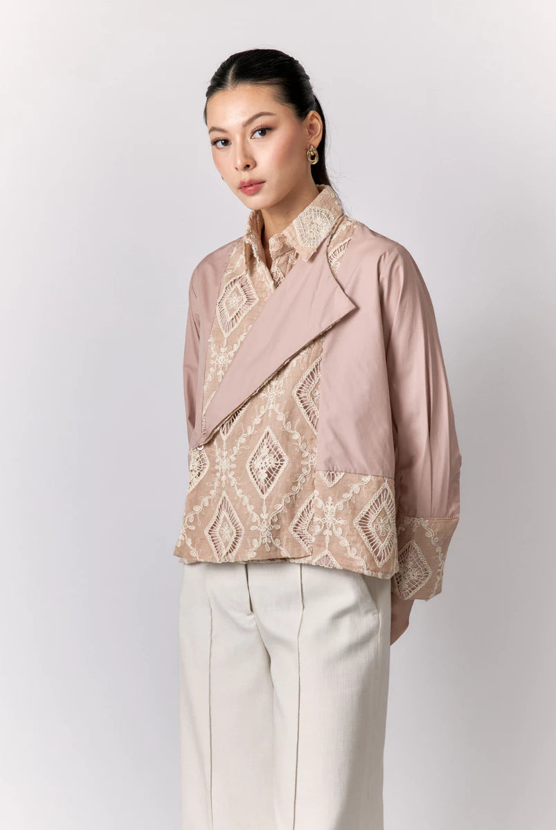 Woman wearing a pink shirt by Studio Tui with intricate patterns on a white background