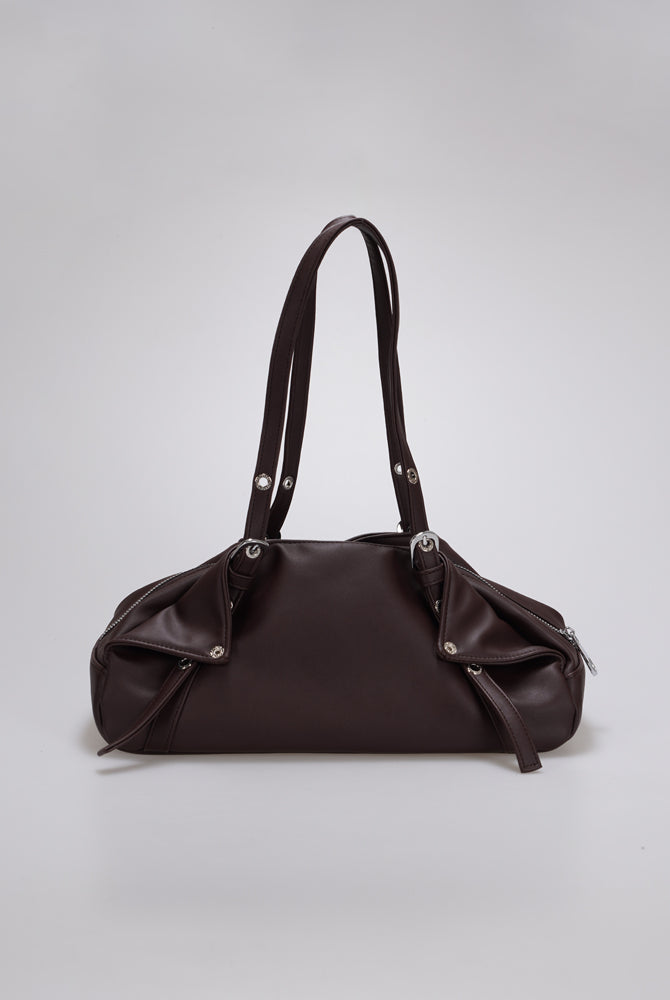 A dark brown leather shoulder bag by Cekhas with a slouchy, rounded silhouette, dual shoulder straps, and silver-tone hardware, photographed against a neutral light gray background.