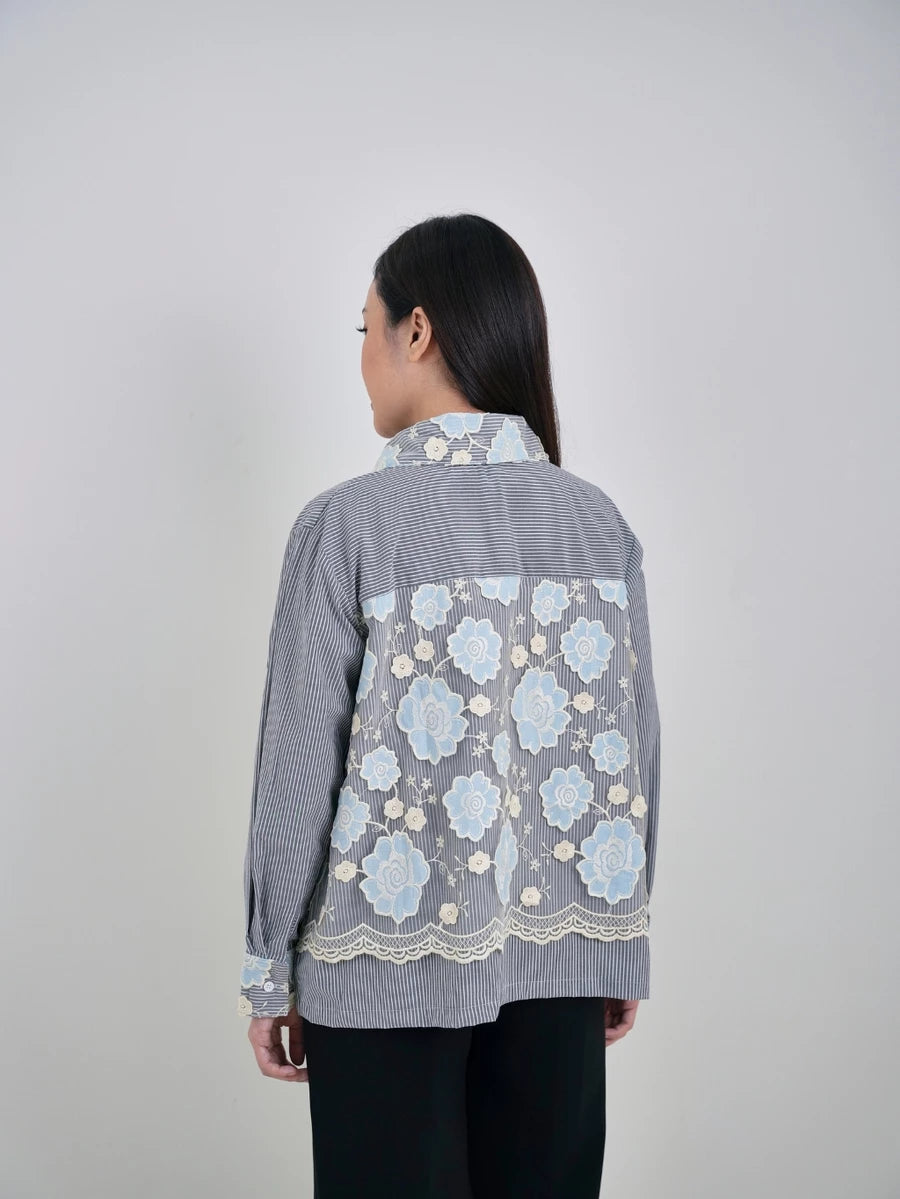 Woman wearing a gray shirt by Studio Tui with floral embroidery on the back.
