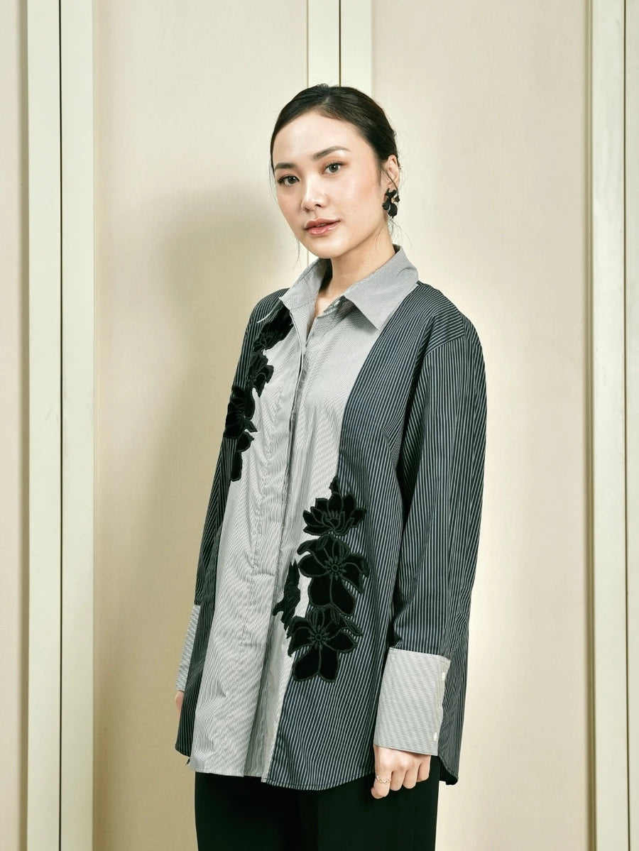 Woman wearing a stylish blue and grey shirt by Studio Tui with floral details against a neutral background