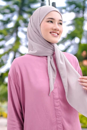 Woman wearing a pink shirt and gray pashmina hijab by Puru Kambera with greenery in the background