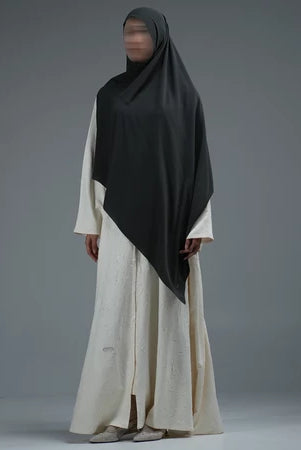 Person wearing a dark grey hijab by Nehhat Modest and white dress on a gray background