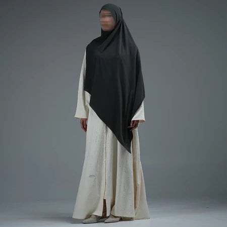 Person wearing a dark grey hijab by Nehhat Modest and white dress on a gray background