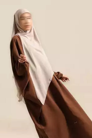 Person wearing a brown dressand beige long hijab by Nehhat Modest on a plain background