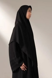 Person wearing a black long hijab by Nehhat Modest against a plain background