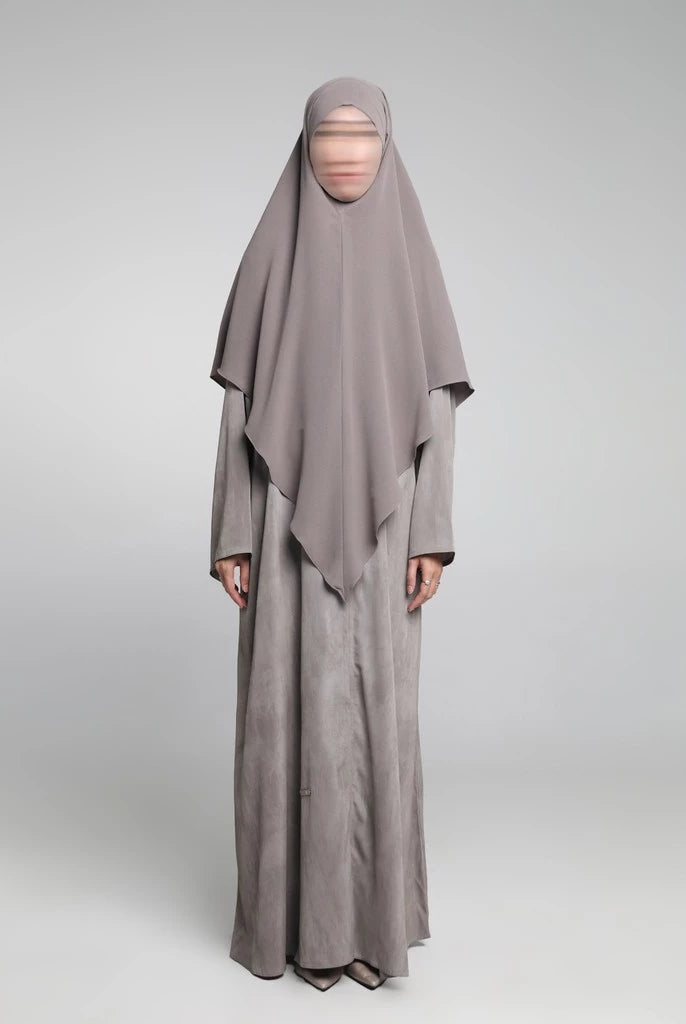 Person wearing a long, light gray Sadda Abaya by Nehhat Modest with a matching headscarf on a white background