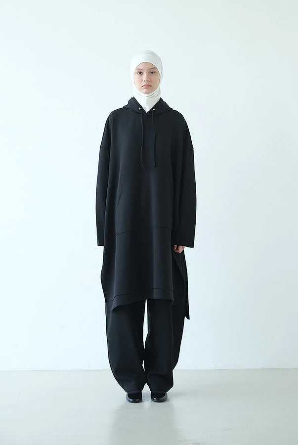 Person wearing a black long hooded sweatshirt by Rashawl with a white headscarf on a white background