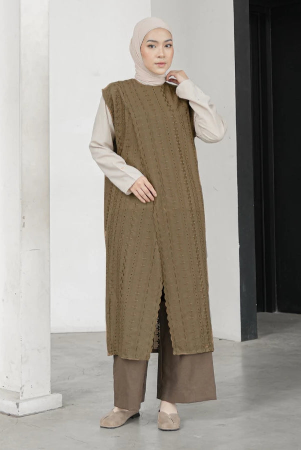 Woman wearing a long brown textured vest by Mistyvori with a white hijab indoors.