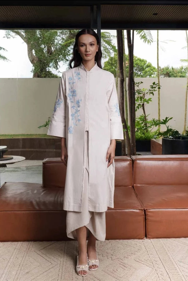 Woman in a light-colored tunic by Jenna & Kaia standing in a modern indoor setting with a brown leather sofa and glass doors.
Seorang wanita mengenakan tunik berwarna terang dari Jenna & Kaia berdiri di dalam ruangan modern dengan sofa kulit cokelat dan pintu kaca.