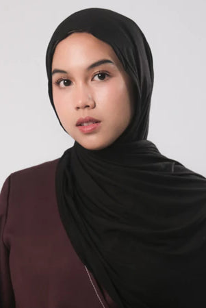 A woman wearing a black bamboo pashmina airflow by Tantri Namirah with a maroon garment.