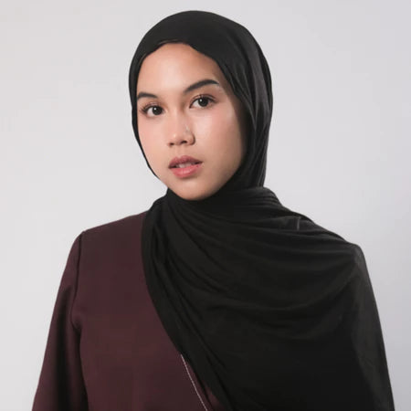 A woman wearing a black bamboo pashmina airflow by Tantri Namirah with a maroon garment.