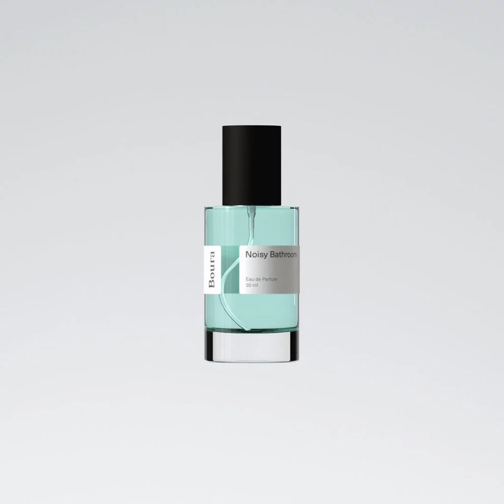 Perfume bottle with a black cap and light blue liquid from Boura on a gray background