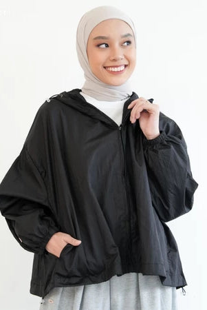 Woman wearing a black jacket by Mistyvori and beige hijab on a white background
