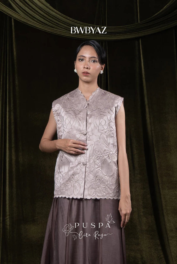 Woman wearing a taupe-colored sleeveless embroidered vest and skirt with 'BWBYAZ' branding.