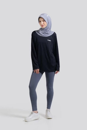 Woman wearing a black long-sleeve top by Noore and gray leggings with a hijab on a white background