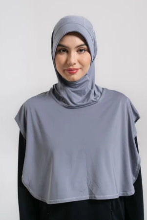 Woman wearing a dark gray hijab sport by Noore and black outfit against a white background