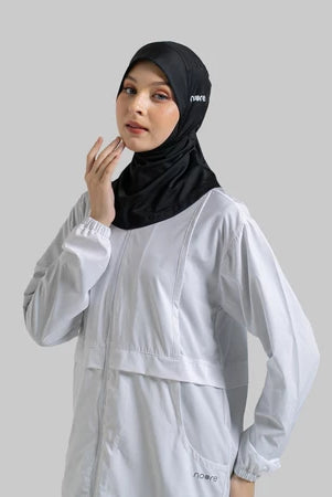 Woman wearing a black sport hijab by Noore and light gray outfit on a plain background