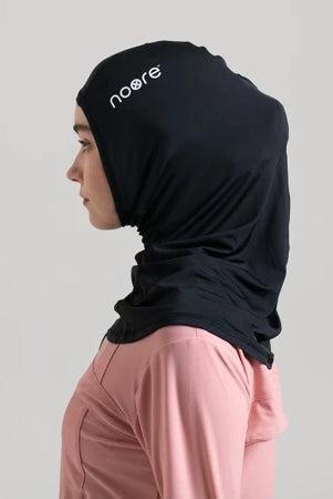 A woman wearing a black headscarf with the brand 'noore' visible on the front