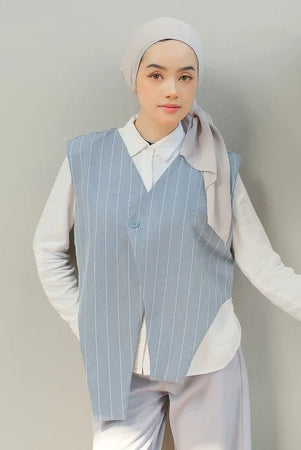 Person wearing a light blue pinstripe vest by Tunique over a white shirt with a plain background