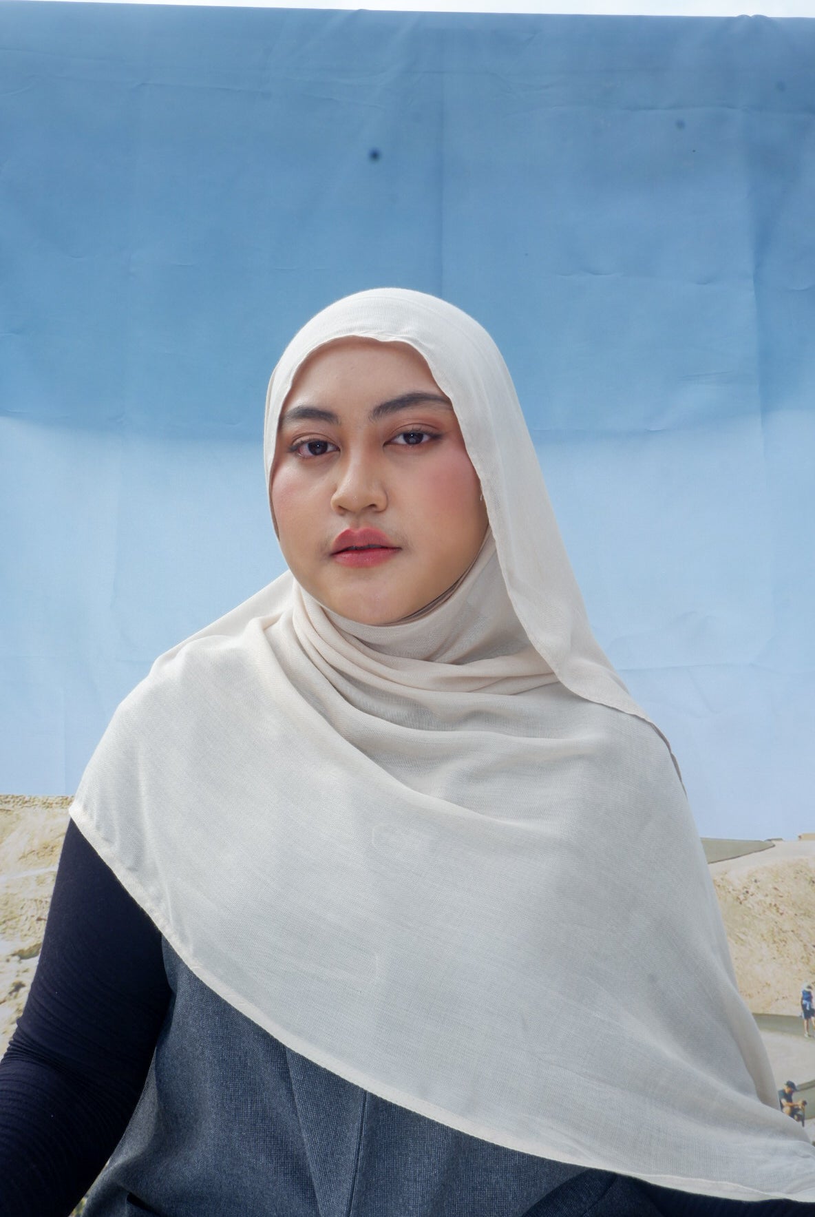 Person wearing a ivory hijab pashmina viscose against a blue sky and desert landscape