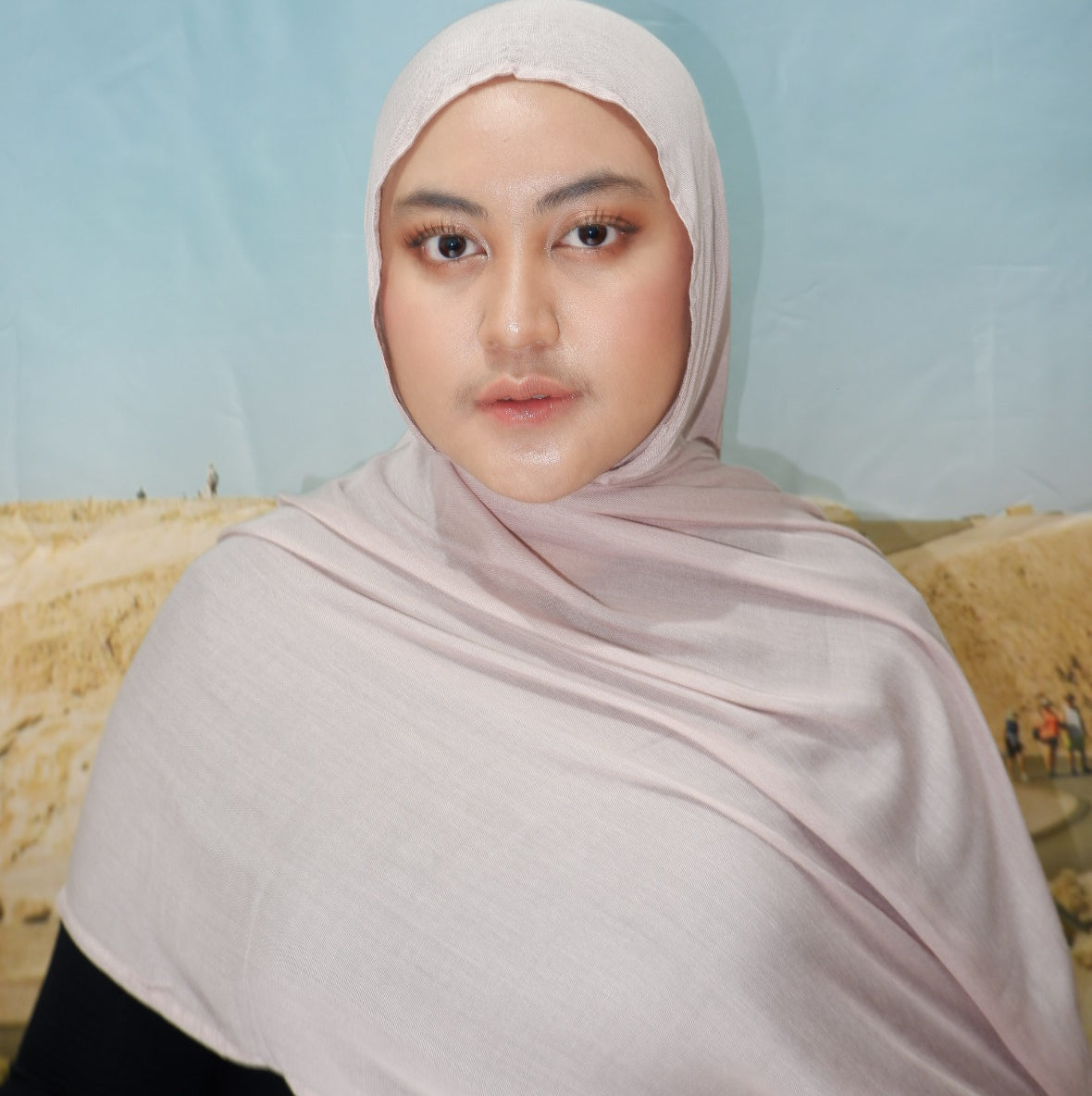 Person wearing a light pink hijab pashmina viscose against a light blue background