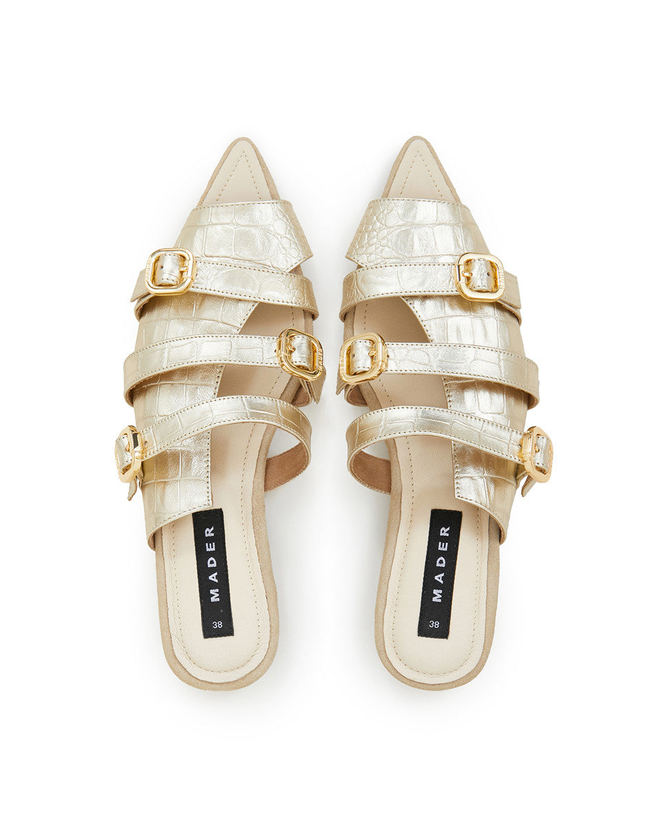 A pair of gold open toe mules with crocodile pattern leather upper and buckle details. The brand's signature outsole is visible.