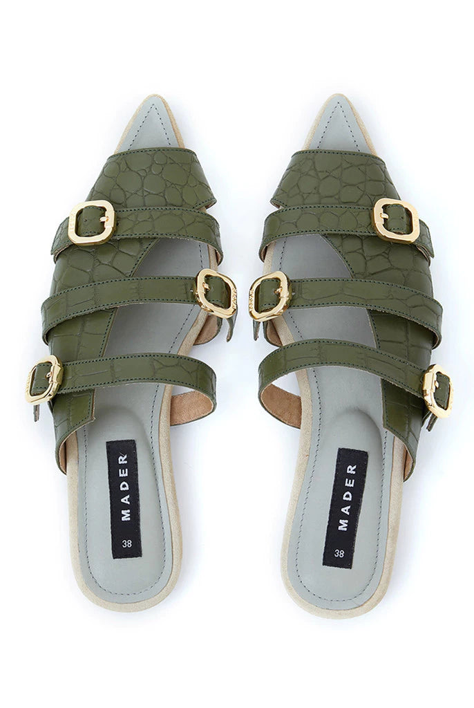 A pair of green crocodile patterned open toe mules with buckle straps and a flat sole.