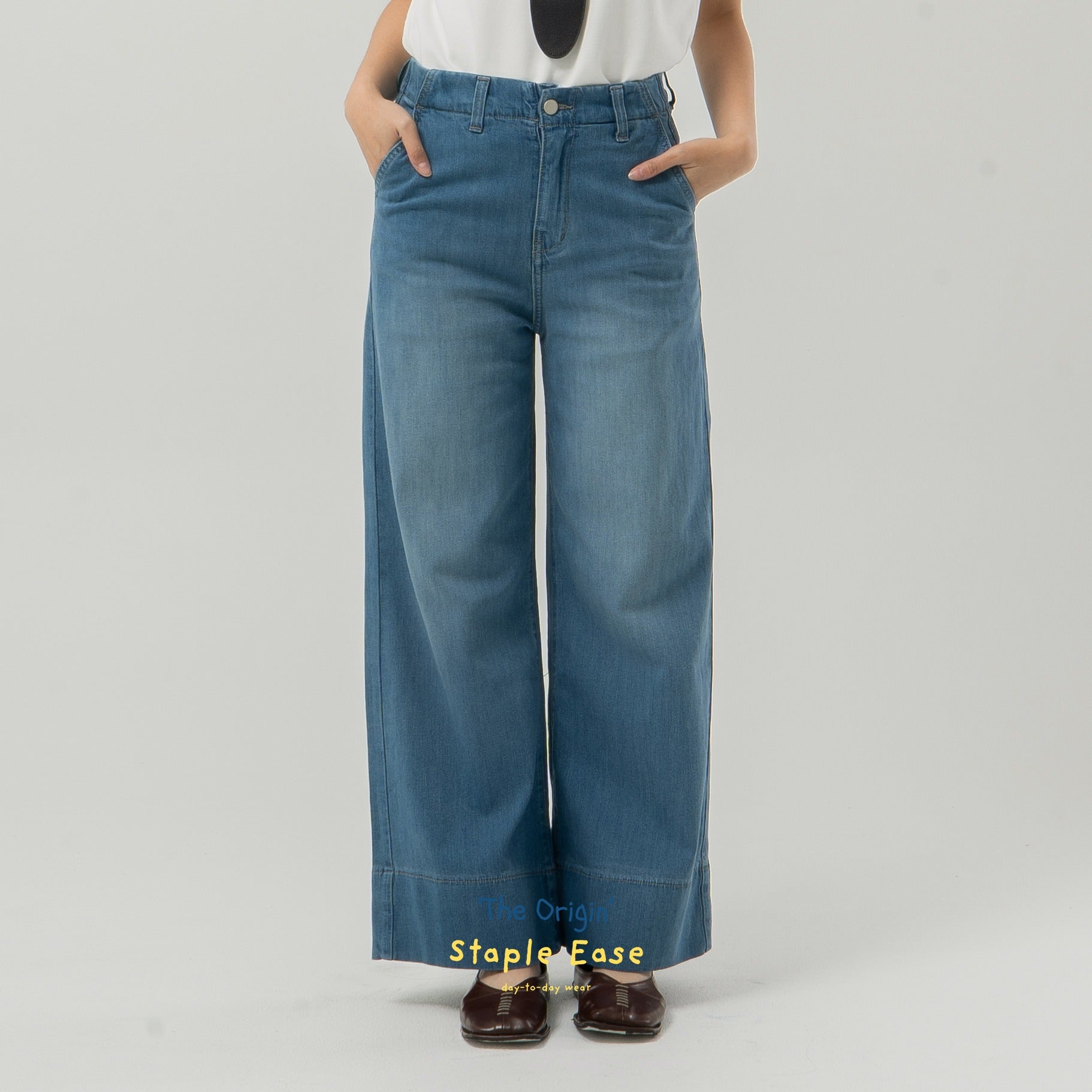 Blue wide-leg jeans from BWBYAZ worn by a person on a gray background.