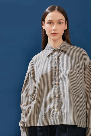 Person wearing a brown striped shirt by Yestoday against a blue background