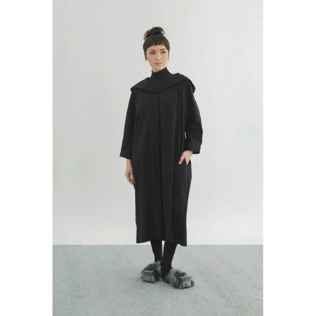 Person wearing a long black dress by Yestoday with a high collar on a plain background