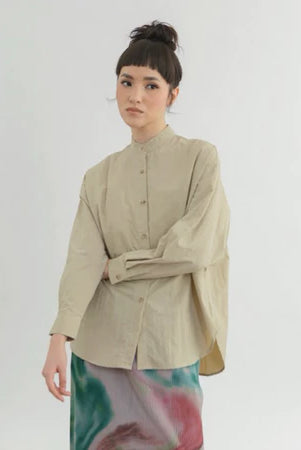 Woman wearing a beige boxy shirt by Yestoday with a tie-dye skirt on a white background