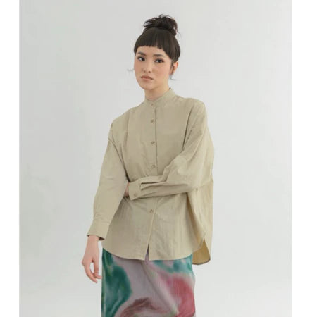 Woman wearing a beige boxy shirt by Yestoday with a tie-dye skirt on a white background