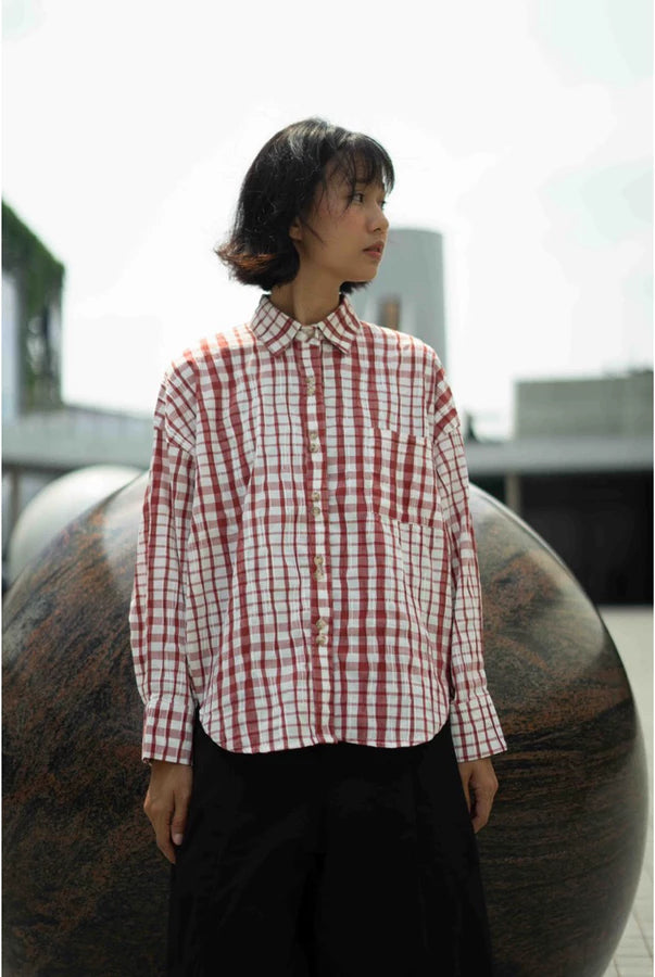 Person wearing a red and white checkered shirt by Yestoday standing in front of a large spherical object.