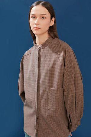 Woman wearing a brown checkered oversized shirt by Yestoday against a blue background