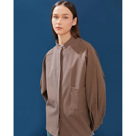 Woman wearing a brown checkered oversized shirt by Yestoday against a blue background