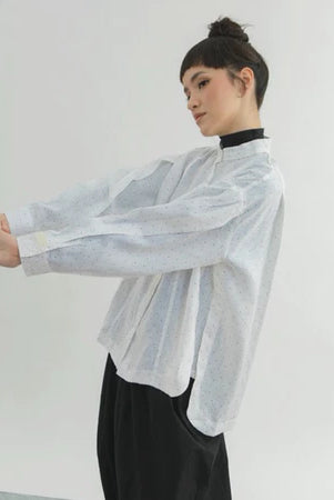 Person wearing a sheer dotted white shirt by Yestoday over a black turtleneck with a plain background