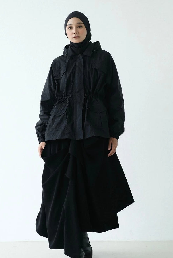 Person wearing a black hooded parka by Rashawl with a hijab against a white background