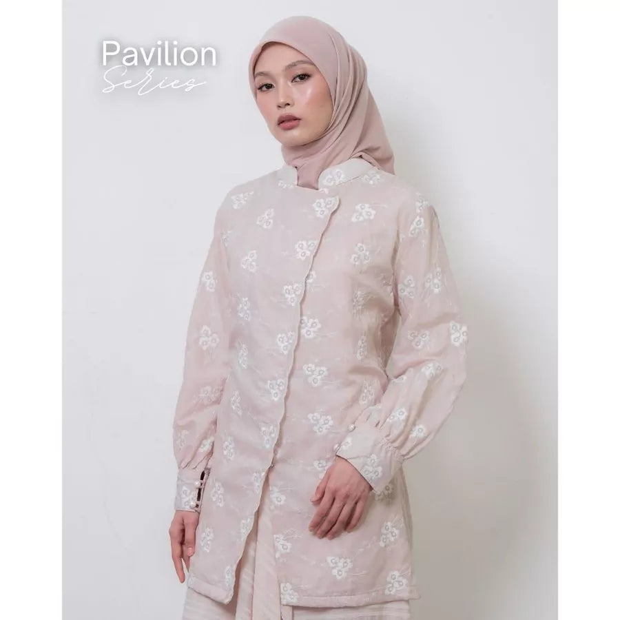 Woman wearing a light pink tunic by Atala Scarves with floral patterns on a white background.
Seorang wanita mengenakan tunik berwarna pink muda dari Atala Scarves dengan motif bunga pada latar belakang putih.