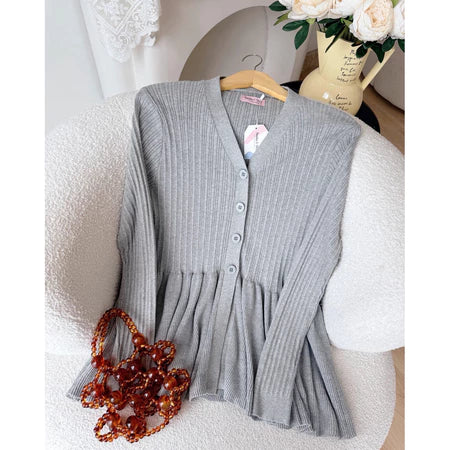 Gray ribbed cardigan from Haidee Orlin on a chair with a decorative bag and flowers in the background