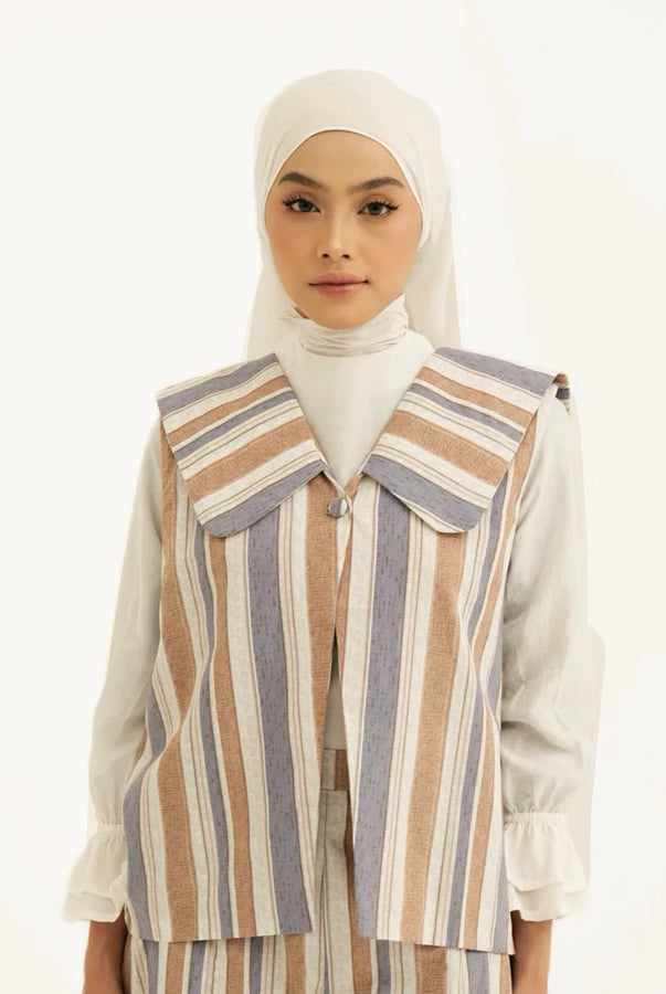 Woman wearing a striped vest by Tunique over white top with a hijab on a white background