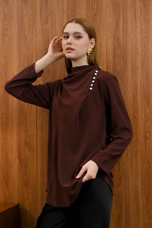 Woman wearing a brown Rachel Blouse by Kasa Heritage with pearl details against a wooden background
