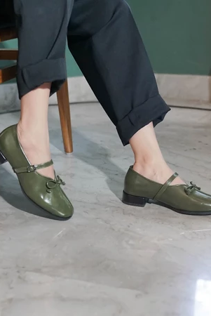 A person wearing green, pointed, flat shoes with a buckle strap across the foot by Dianable.