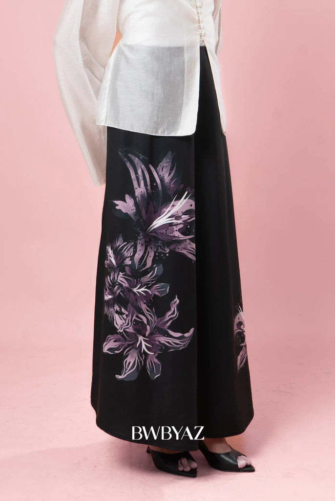 Black skirt with floral pattern worn by a person on a pink background, with 'BWBYAZ' branding.