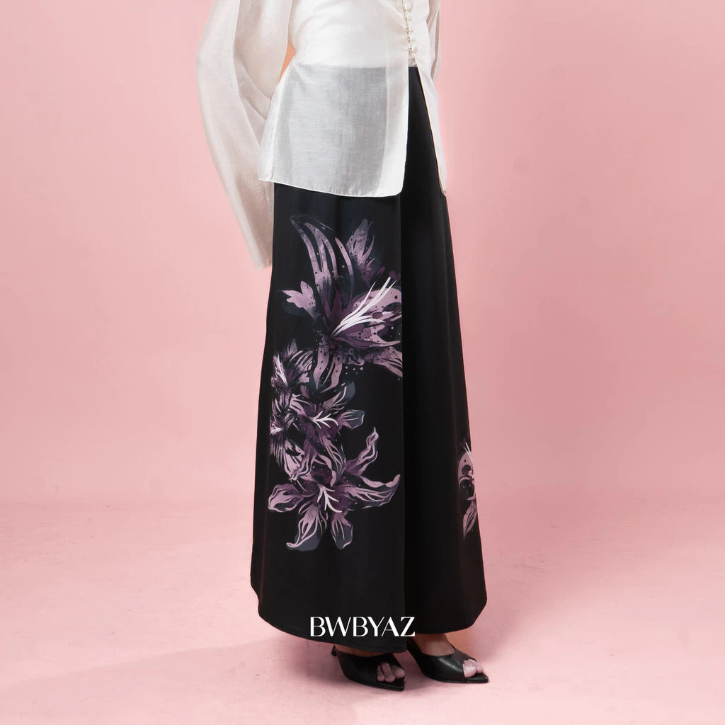 Black skirt with floral pattern worn by a person on a pink background, with 'BWBYAZ' branding.