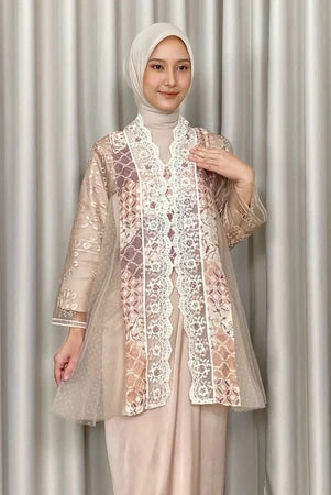 Woman wearing a beige lace kebaya by Kartinis Label and hijab against a neutral background
